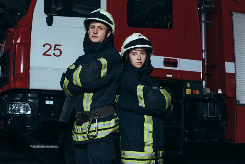 Firefighters in turnout gear standing in front of their engine